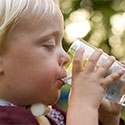 Boy with tracheostomy drinking from water glass